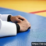 Home 21 유도 도복 커스터마이징 - A confident adult male judoka wearing a custom-fitted white judogi with subtle blue color accents on...